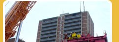 Placing boom and lifting gear working on a building frame.
